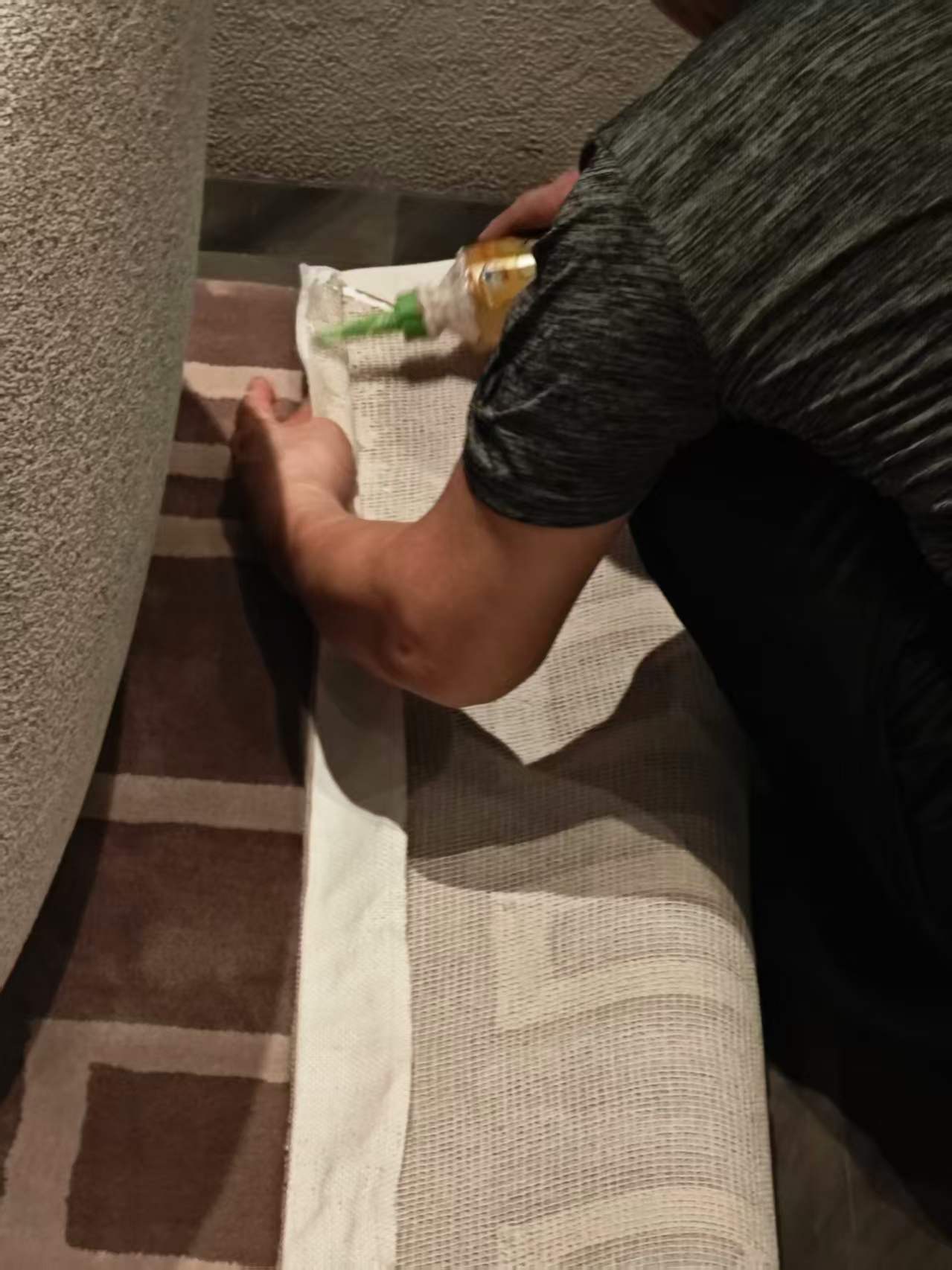 工人在现场沿地毯边缘处理外露的包边白布